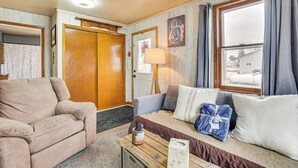 A cozy living room with a beige sofa, a wooden coffee table, and a window with curtains.
