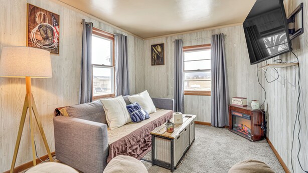 A cozy living room with a sofa, a coffee table, a fireplace, and a mounted TV.