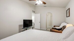 Ein Schlafzimmer mit Bett, Deckenventilator, Fernseher, Tür und Spiegel.