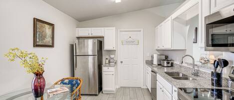 A modern kitchen with white cabinets, stainless steel appliances, and a glass dining table.