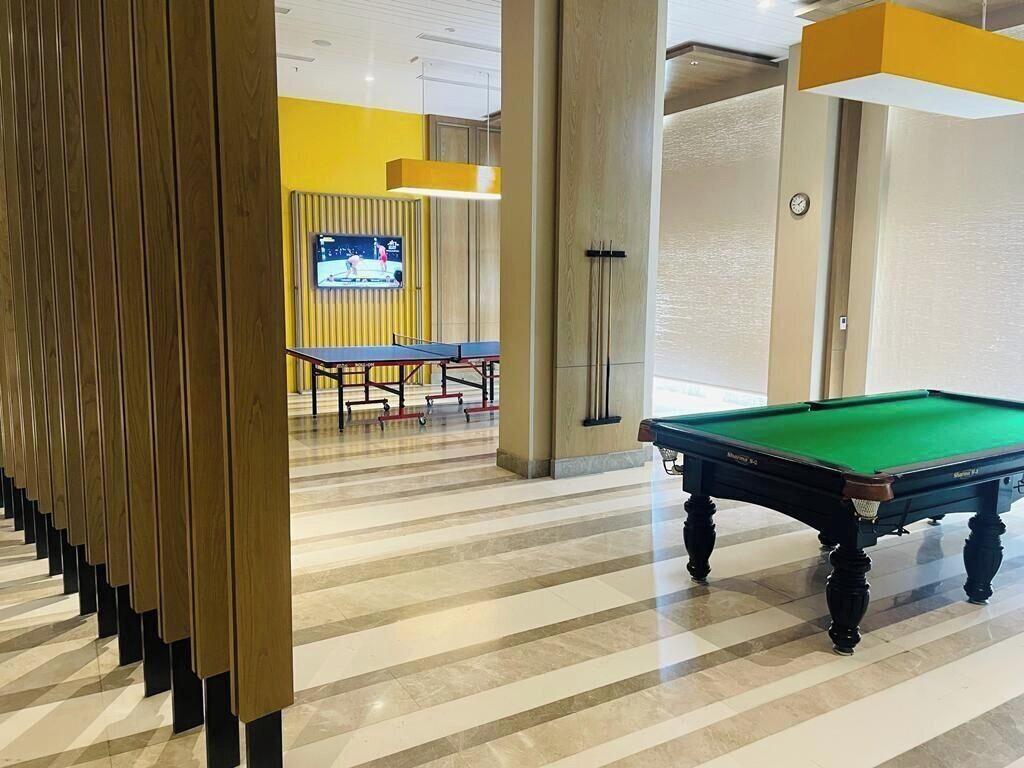 A pool table in a room with striped flooring and a television in the background.