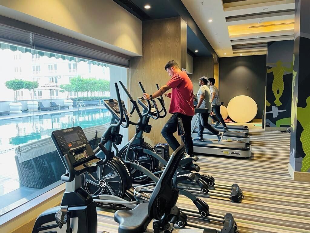 Un gimnasio con cintas de correr y vista a la piscina.