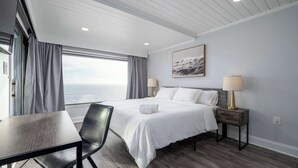 A modern hotel room with a large bed, a desk, and a view of the sea. - Extraordinary 3BR Oceanfront Escape | 2 Balconies (Ocean City)