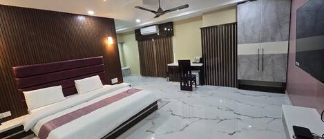 A modern bedroom with a large bed, a desk, and a wardrobe.