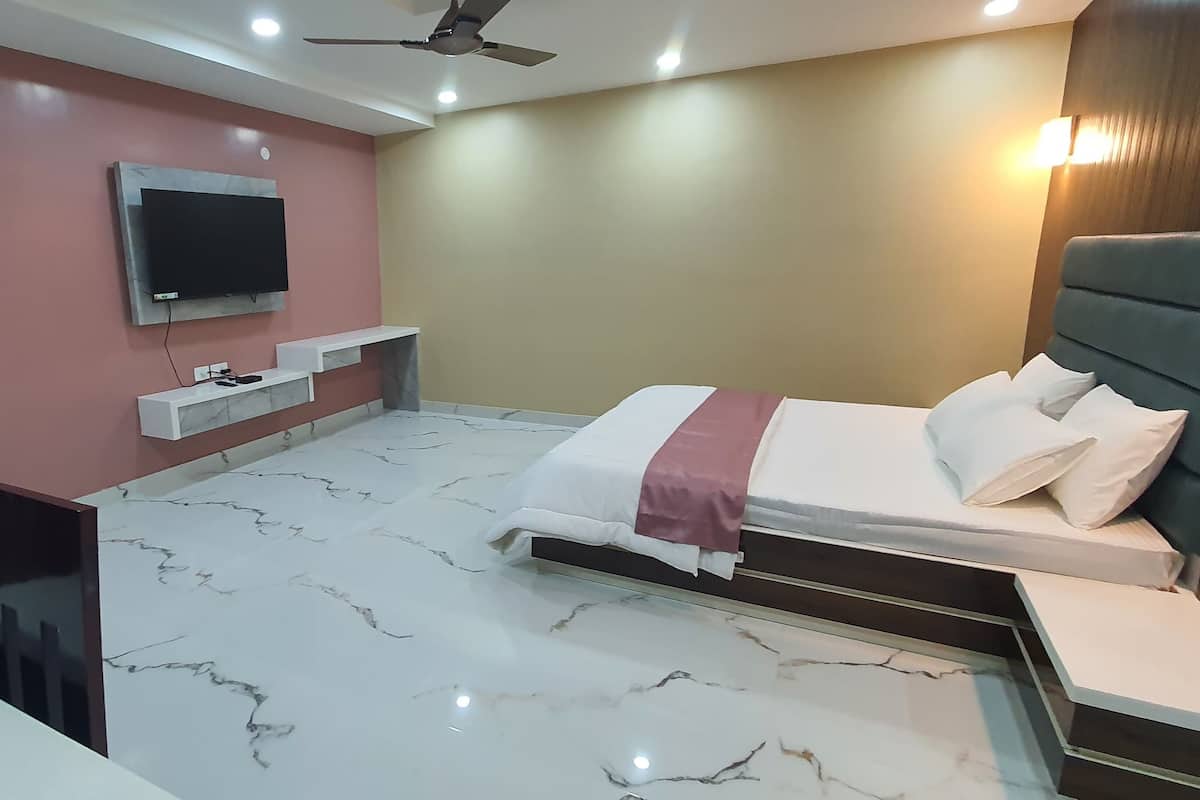 A hotel room with a bed, a TV mounted on the wall, a ceiling fan, and a marble floor.