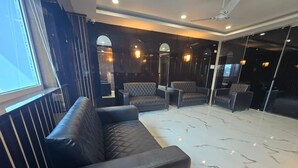 A modern living room with a black leather sofa, a glass partition, and a marble floor. - SC Hotel (Papumpare)