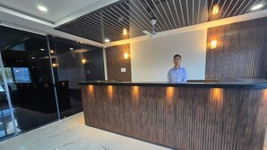 A reception desk with a modern design, featuring a wooden panel and a glass partition. - SC Hotel (Papumpare)