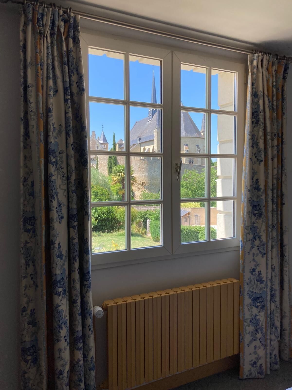 A room with a large window, a radiator, and curtains.