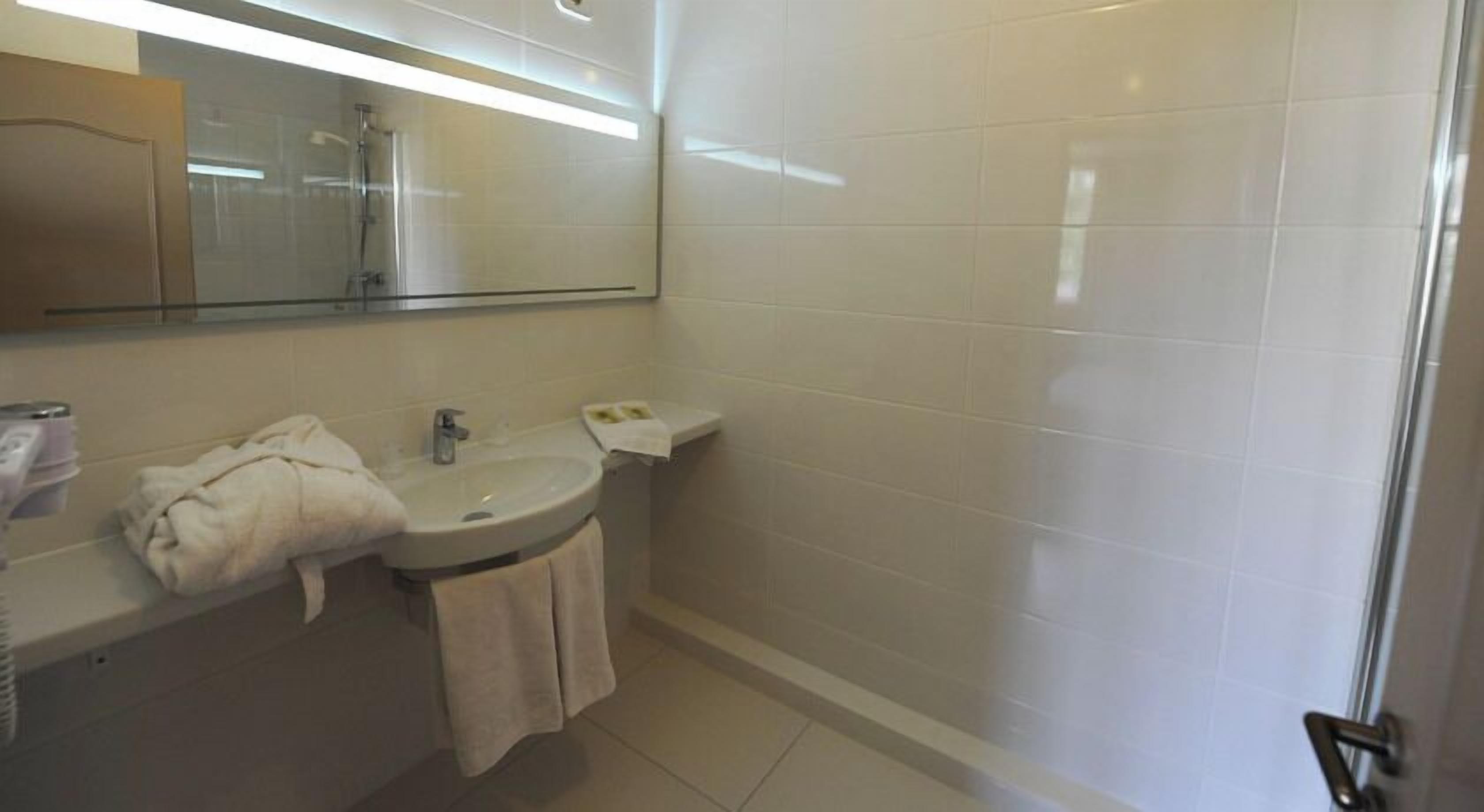 Baño con lavamanos, espejo y ducha.