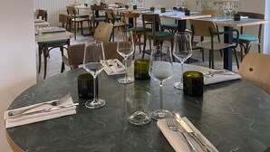 A restaurant with round tables, chairs, and hanging light fixtures.