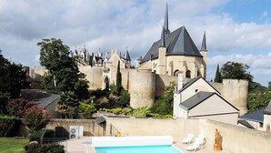A castle with a swimming pool and lounge chairs in the foreground.