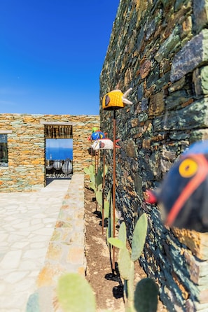 A stone wall with a cactus garden and a metal sculpture. - Makarias Traditional Luxury Villas (Folegandros)
