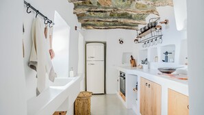 A modern kitchen with white cabinetry, a stone ceiling, and a built-in oven.