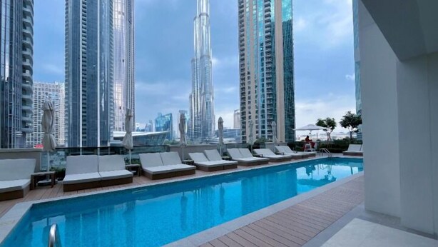 A rooftop pool with lounge chairs, surrounded by high-rise buildings. - ACTONE Tower2-Step to Burjkhalifa-1BR (Dubai)