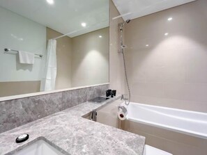 Ein Badezimmer mit Marmorwaschbecken, einer Badewanne, einer Dusche und einem auf einem Handtuchhalter hängenden Handtuch.