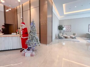 Eine moderne Hotelhalle mit einer Rezeption, einem Weihnachtsbaum und einer Sitzecke mit Sofas und einem Couchtisch.