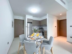 Eine moderne Küche mit Kühlschrank, Mikrowelle und Herd. Es gibt einen Essbereich mit Tisch und Stühlen sowie eine kleine Pflanze auf dem Tisch.