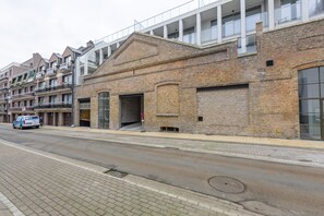A street view with a row of brick buildings, a van parked on the side, and a pedestrian crossing. - Newly Built Studio on 1st Floor With Terrace (Middelkerke)