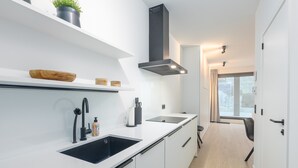 A modern kitchen with white cabinetry, black countertops, and a black range hood. - Newly Built Studio on 1st Floor With Terrace (Middelkerke)