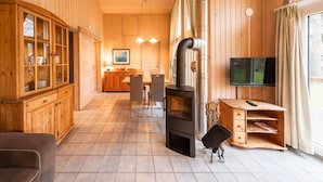 A wooden interior with a fireplace, a television, and a dining area. - Ferienhaus mit Sauna im Ferienpark Mirow (Mirow)