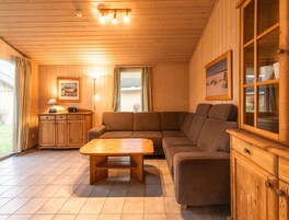 L’intérieur d’un chalet en bois chaleureux et accueillant, avec un canapé, une table en bois, un meuble et un tableau encadré accroché au mur.