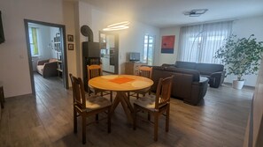 Un salon moderne comprenant un canapé, une table à manger avec des chaises, un coin cuisine et une grande fenêtre avec des rideaux.