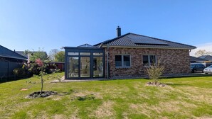 Een modern huis met een glazen voordeur, een bakstenen gevel en een pannendak.
