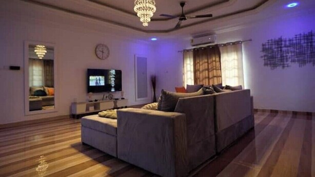 Een moderne woonkamer met een grote modulaire bank, een flatscreen televisie en een kroonluchter.