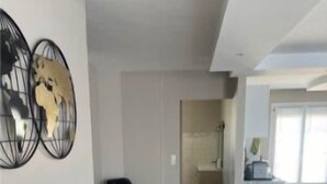 Un salón amplio con diseño moderno, que incluye una silla negra, una mesita pequeña y dos obras de arte abstracto en la pared.
