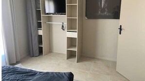 Un dormitorio con una cama, un armario, un televisor y un cuadro con un elefante.