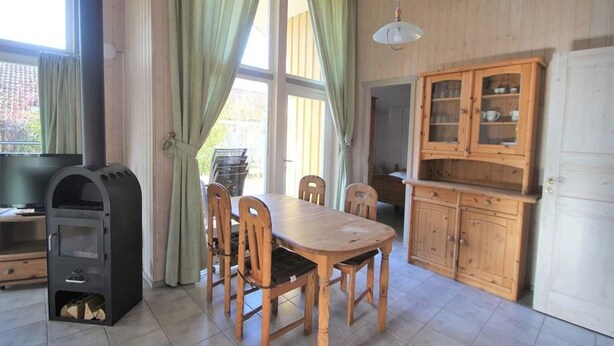 Un comedor con una mesa y sillas de madera, horno empotrado y un mueble con puertas de cristal.