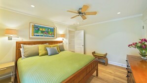 A bedroom with a bed, a ceiling fan, a nightstand, a lamp, a door, and a wall-mounted painting. - Beachside in Seaside, FL, 3 King Suites, Amazing Gulf Views - 2 Adult Bikes! (Santa Rosa Beach)