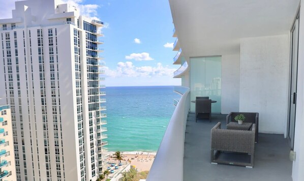 A balcony with a view of the ocean and a high-rise building.