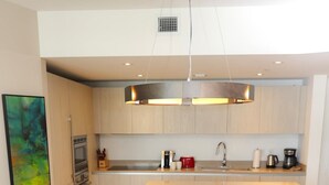 A modern kitchen with a central island, a dining table with four chairs, and a painting on the wall.