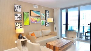 Una sala de estar moderna con un sofá color beige, una mesa de centro de madera y un amplio ventanal con vistas a la ciudad.