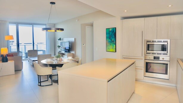 A modern kitchen with a central island, built-in appliances, and a dining area with a round table and chairs.