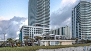 Un hotel de gran altura con fachada curva, varios balcones y ubicación frente a la playa.