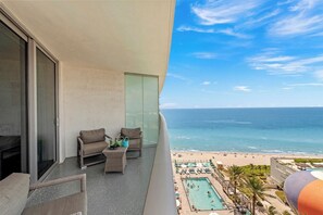 Een balkon met uitzicht op de oceaan en een zwembad.