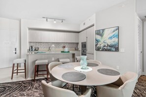 Een moderne keuken met een eetgedeelte, met een ronde tafel met stoelen, een kookeiland en een schilderij aan de muur.