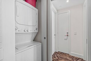 A laundry area with a washing machine and dryer, a door with a handle, and a patterned rug on the floor.