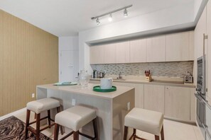 Een moderne keuken met een centraal eiland, barstoelen en een spatwand met een geometrisch patroon.