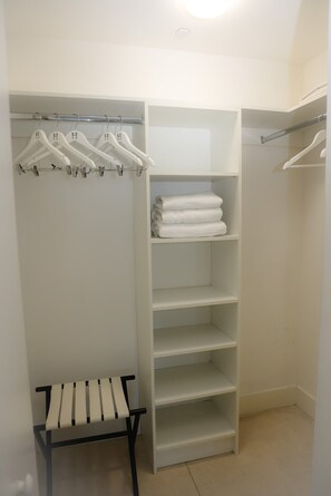 A walk-in closet with white hangers, shelves, and a bench. - Luxury 2BR/2BA Hyde Condo with Direct Beach View (Hollywood)