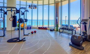 Een sportschool met trainingsapparatuur, een bokszak en uitzicht op de oceaan.