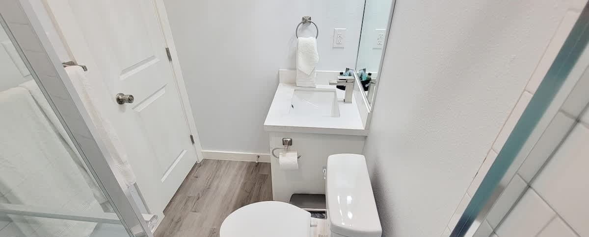 Un baño pequeño y moderno con un inodoro blanco, un lavabo y un espejo encima.