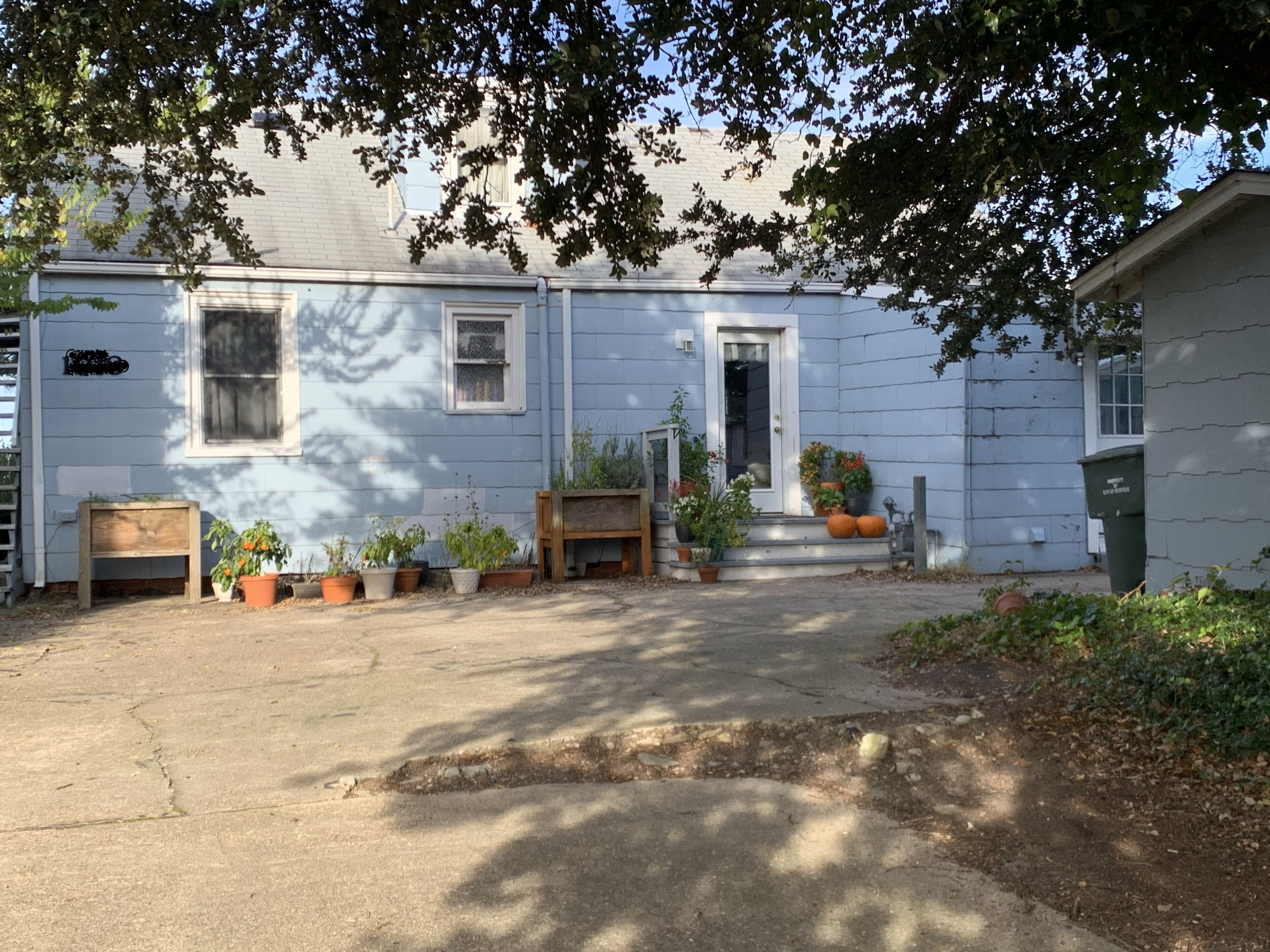 A residential property with a front porch, potted plants, and a wooden bench.