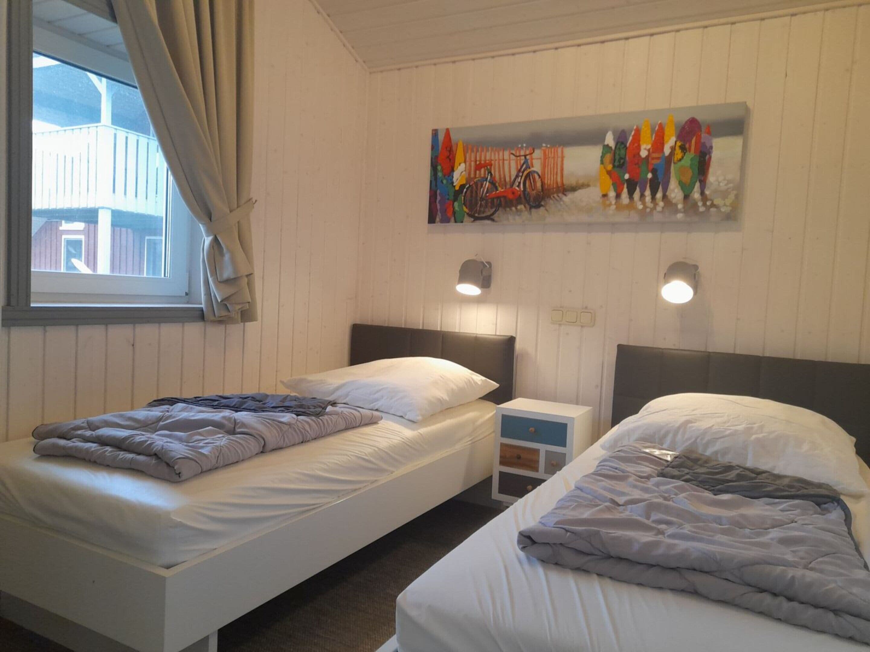 Una habitación con dos camas, una ventana con cortinas, una obra de arte en la pared y lámparas de noche.