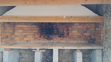 Un four en briques, doté d’une base en béton et d’une structure de toit en bois.