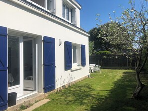 A white building with blue shutters, a grassy yard, and a tree with white flowers. - Carnac House 8/9 persons, ideal for families Between the village and the beach (Carnac)