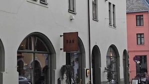 A building with a 'BAR' sign, arched windows, and a cobblestone street. - In the Heart of Brosundet! Fully Equipped 3 Bed Room Ap (Ålesund)