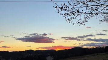 A rural landscape with a sunset, fields, and a distant building.
